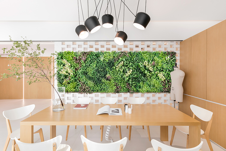 a room with a table and chairs and a wall of plants